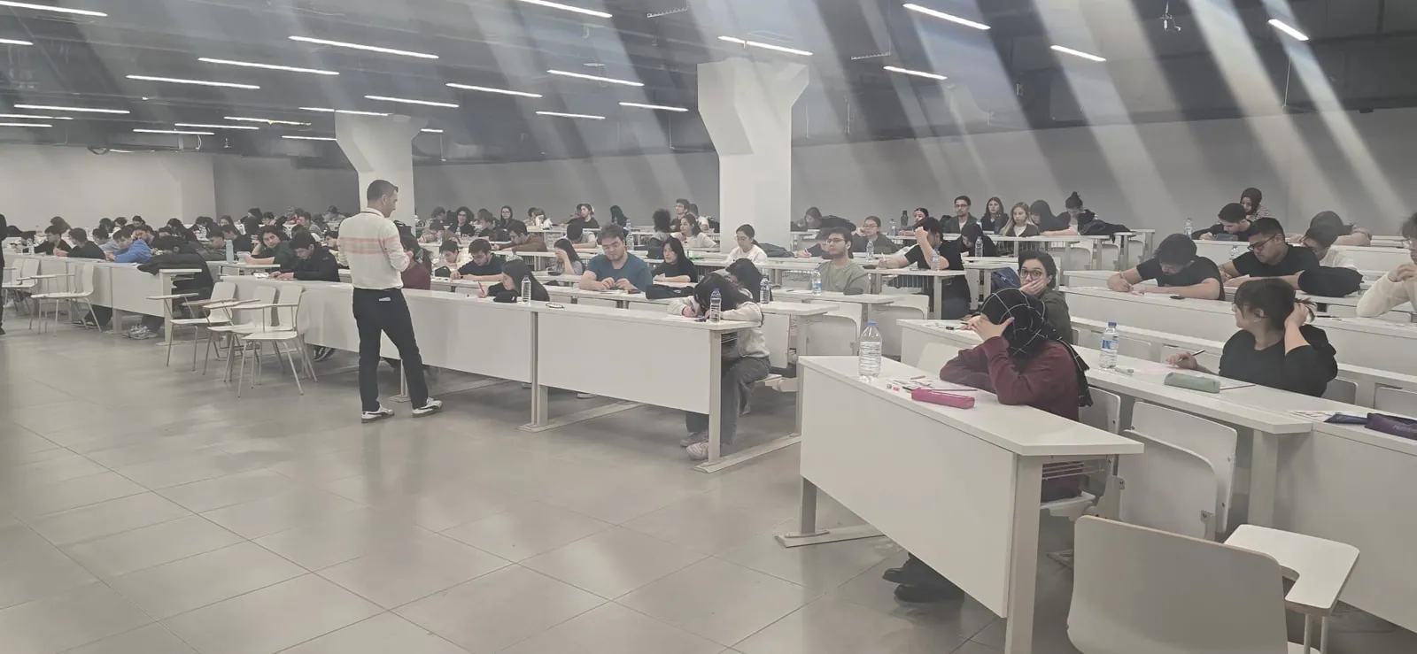 Geniş bir salonda deneme sınavına giren öğrenciler